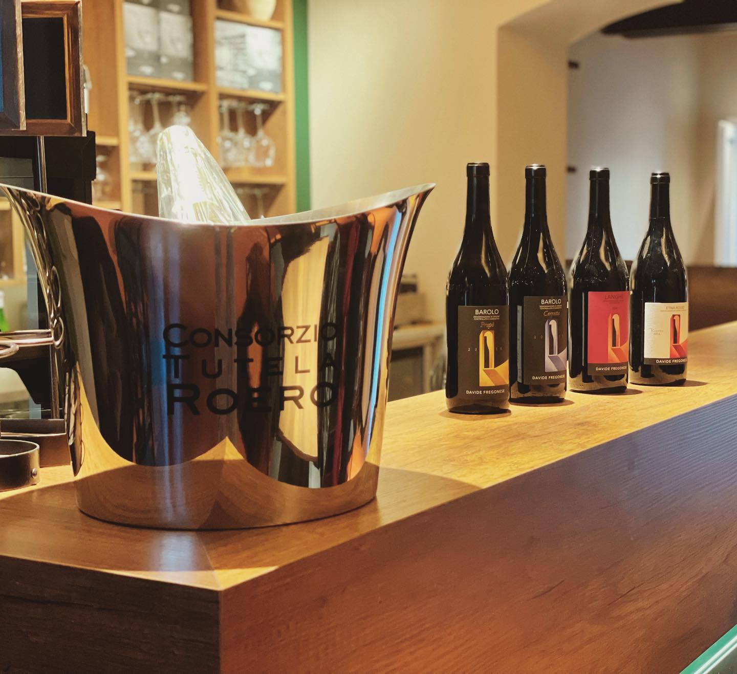 Bancone con secchiello per il vino e bottiglie di Barolo, Langhe, e altri vini