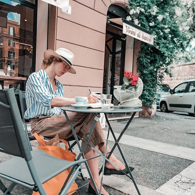 cliente donna scrive al tavolino fuori dal locale di Roma