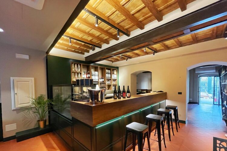 Interno di un bar con soffitto in legno, bancone in legno e marmo, bottiglie di vino esposte