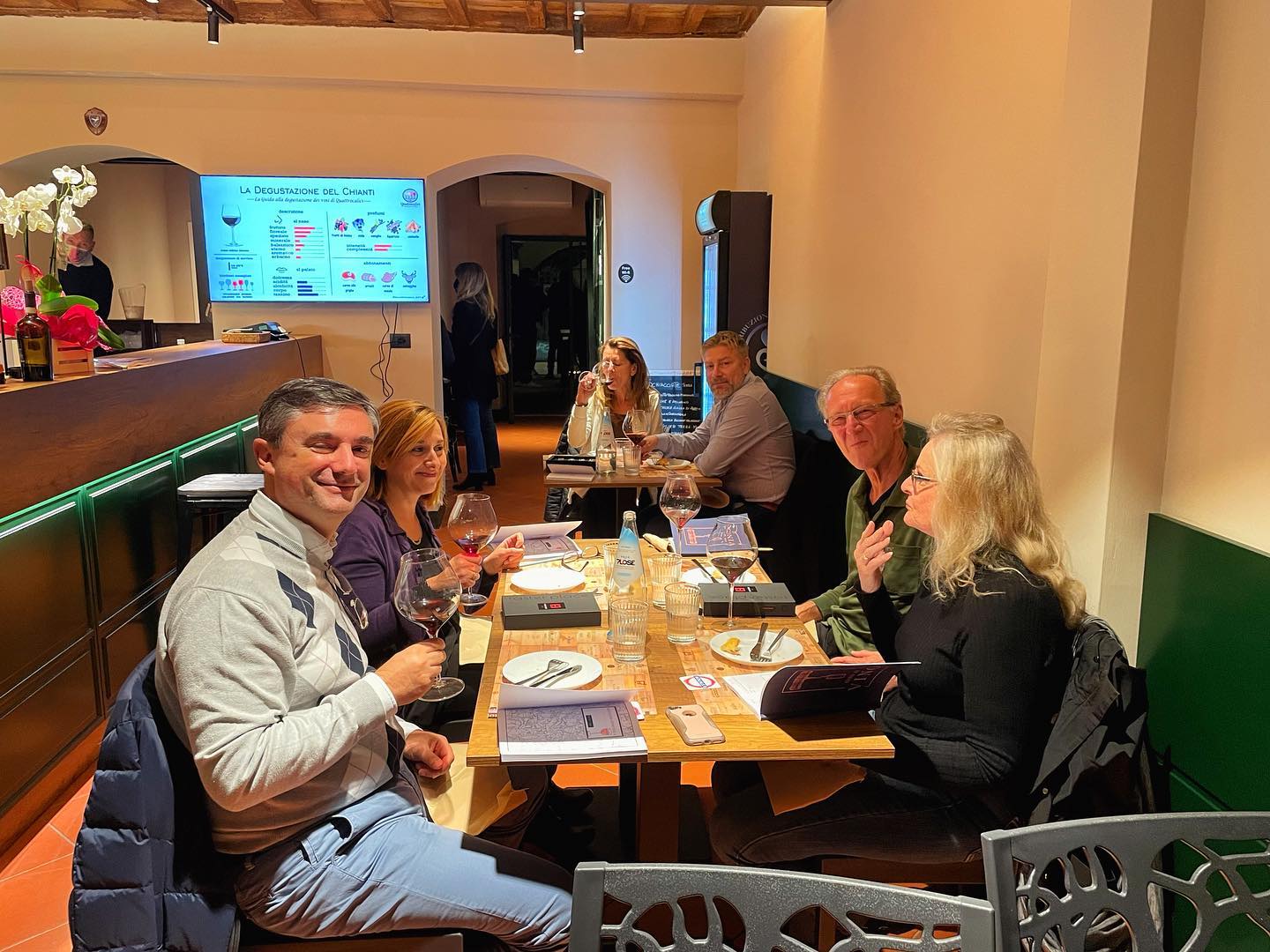 Gruppo di persone a tavola in un locale elegante, degustando vino e conversando