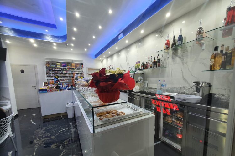 Interno del locale con vetrina pasticceria, scaffali con prodotti e illuminazione moderna