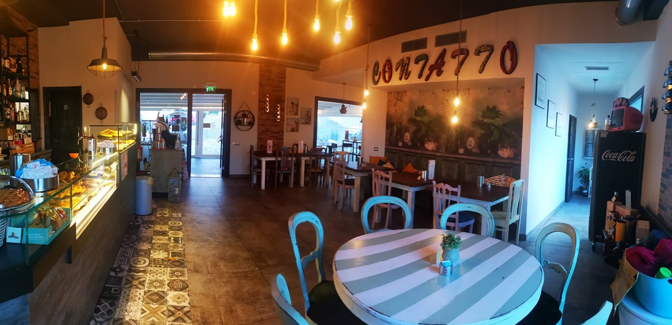 Interno del locale Contaiò Caffetteria Bistrò con bancone pasticceria, tavoli e sedie in legno, illuminazione accogliente