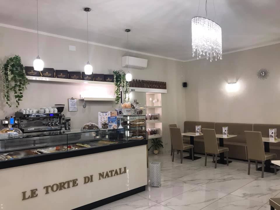 Interno del locale "Le Torte di Natali" con vetrina pasticceria, macchina per caffè, tavoli e sedie eleganti