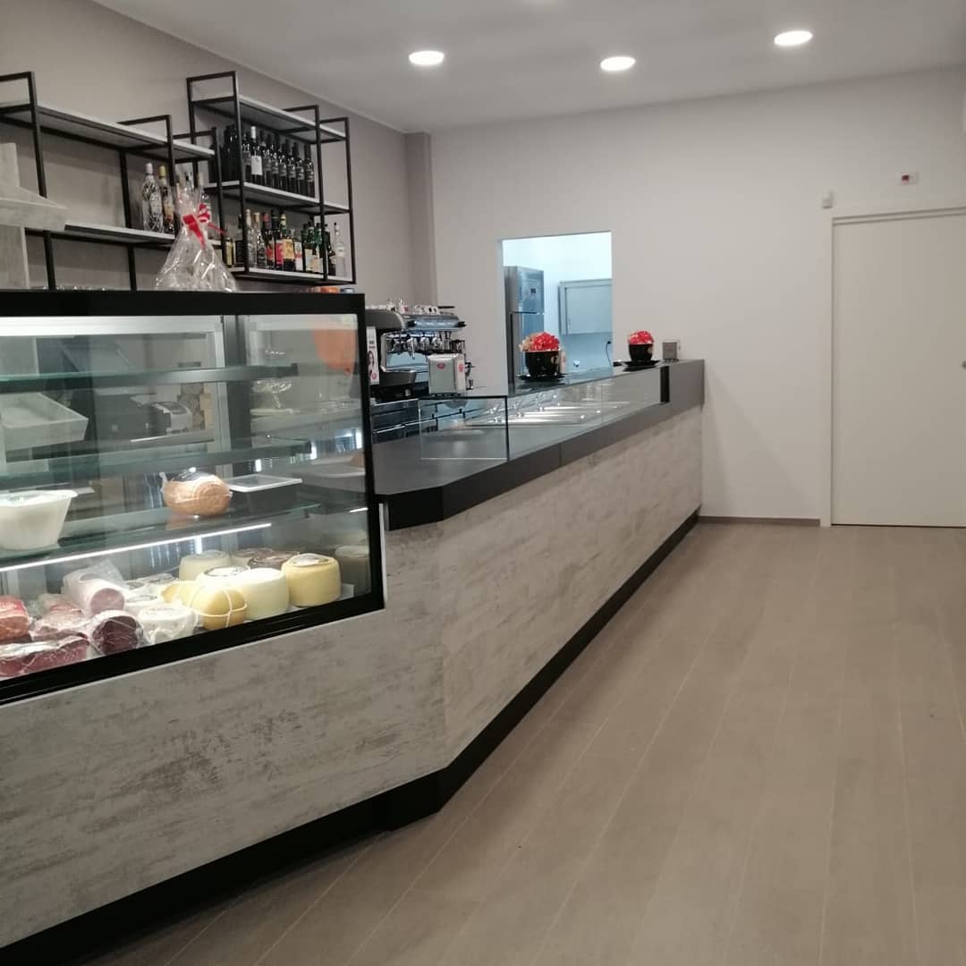 Interno di un bar con bancone moderno e vetrina per alimenti, design by Agape Arredo Bar