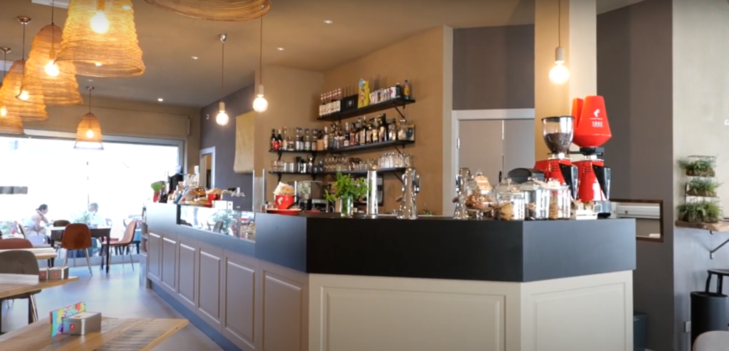 Interno di un moderno caff&egrave; con bancone lungo e illuminazione accogliente, design by Agape Arredo Bar