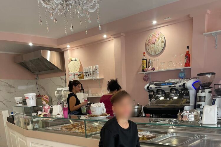 Bambino seduto su uno sgabello dorato in un bar con arredamento rosa e bianco