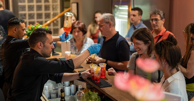 barista-servendo-bevande-gruppo-persone-locale-affollato Barista che serve bevande a un gruppo di persone in un locale affollato