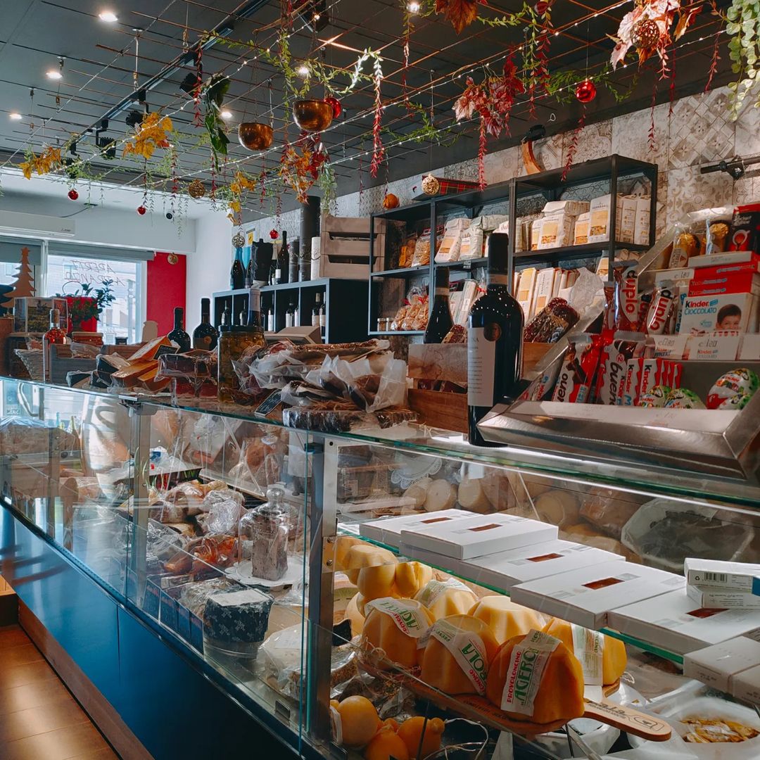 Bancone gastronomia con prodotti alimentari assortiti, scaffali pieni e decorazioni appese