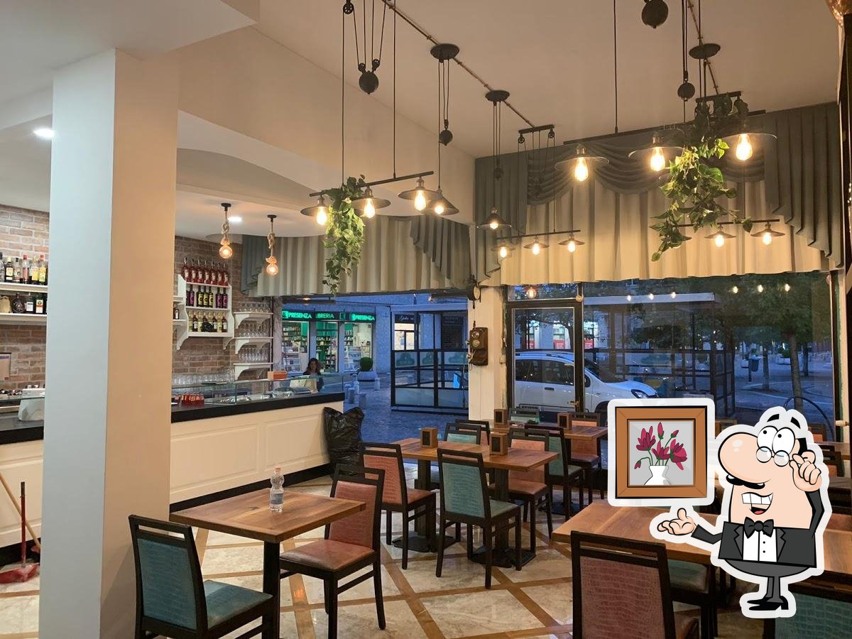 Facciata del bar Vecchia Napoli con due ingressi affiancati, insegne verdi e gialle, e lavoratori visibili all'interno mentre effettuano preparazioni. Auto e biciclette sono parcheggiate davanti al locale. Realizzato da Agape Arredo Bar.