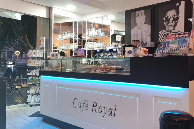 Bancone di un bar moderno con illuminazione LED blu e decorazioni chic, progettato da Agape Arredo Bar